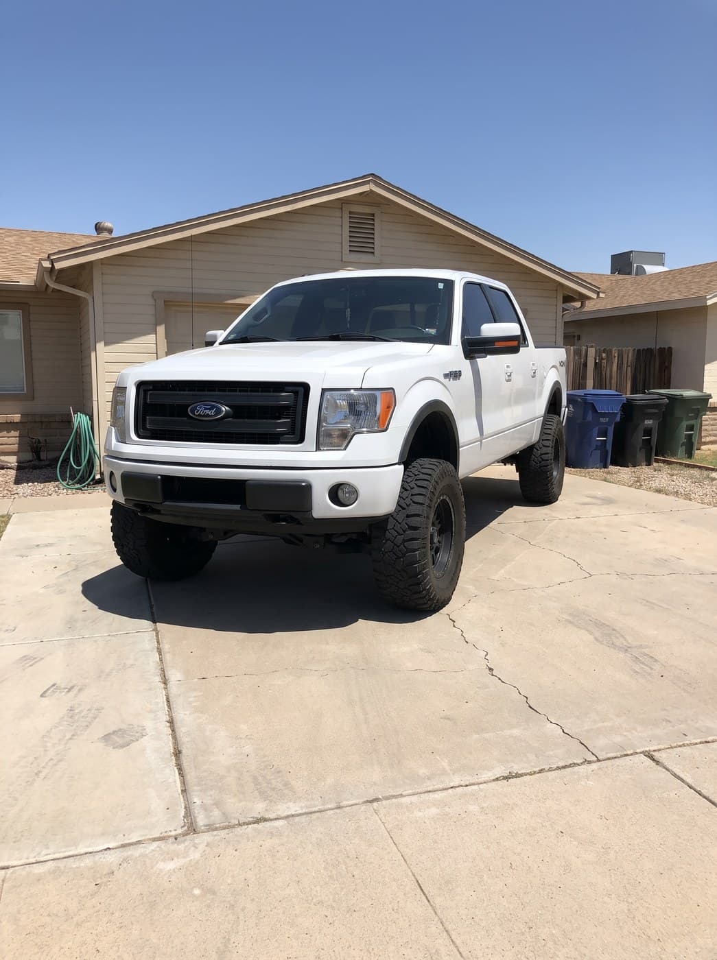 A white lifted Ford F-150 parked on a driveway.